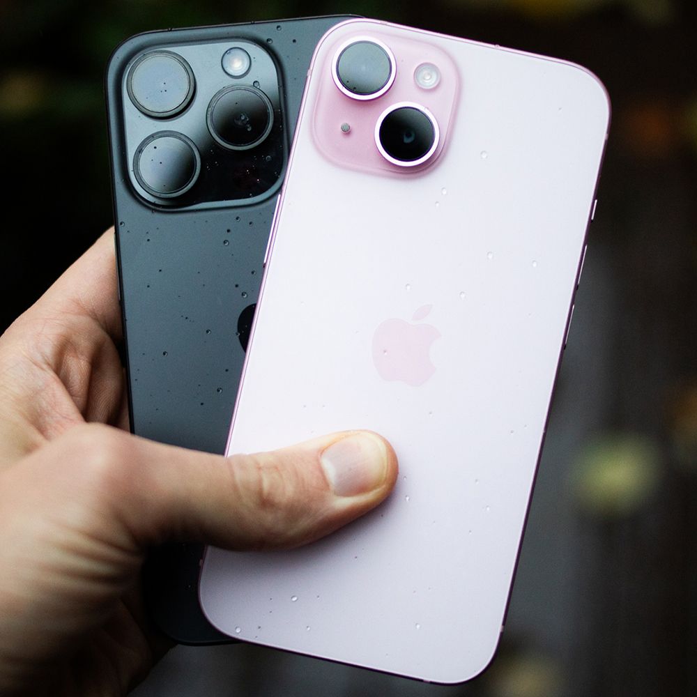 en hånd som holder en svart iphone 15 pro og en rosa iphone 15