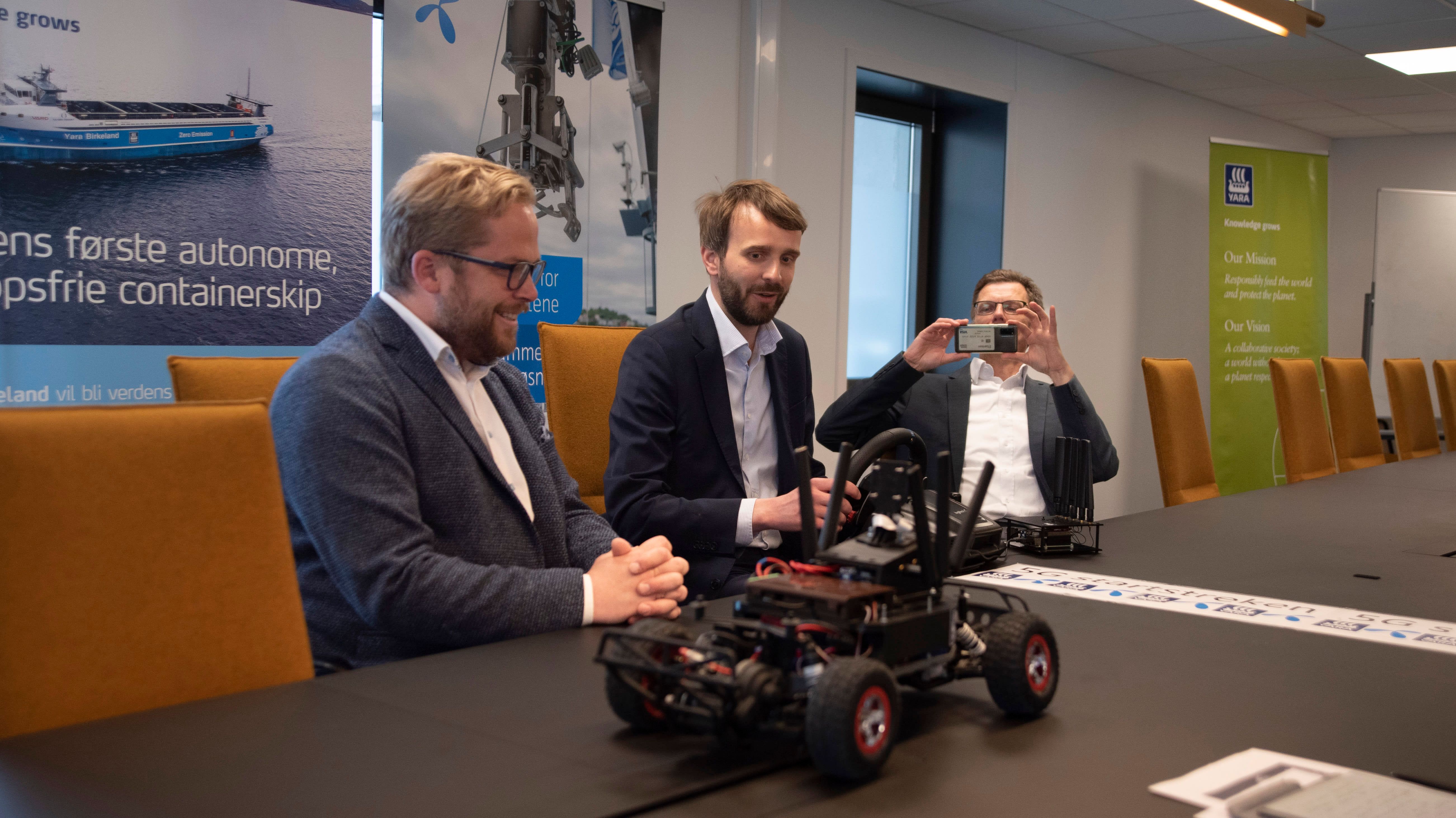Åpningen av industriell 5G på Herøya skjedde ved at næringsminister Jan Christian Vestre kjørte en radiostyrt bil via mobilnettet. Bilen er utviklet av studenter ved NTNU. Vestre er flankert av Lars Røsæg (til venstre) og Petter-Børre Furberg.