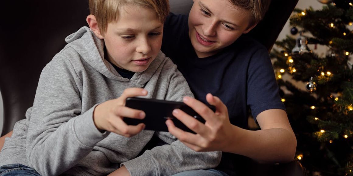 2 brødre ser på mobiltelefon ved juletreet