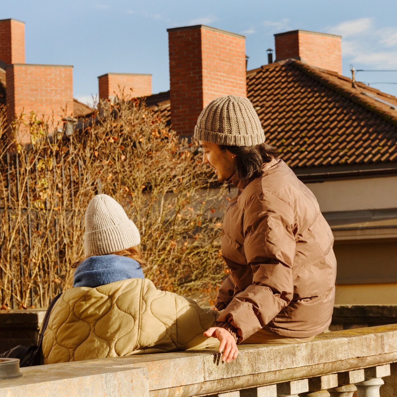 to personer utenfor en boligblokk i vintersolen
