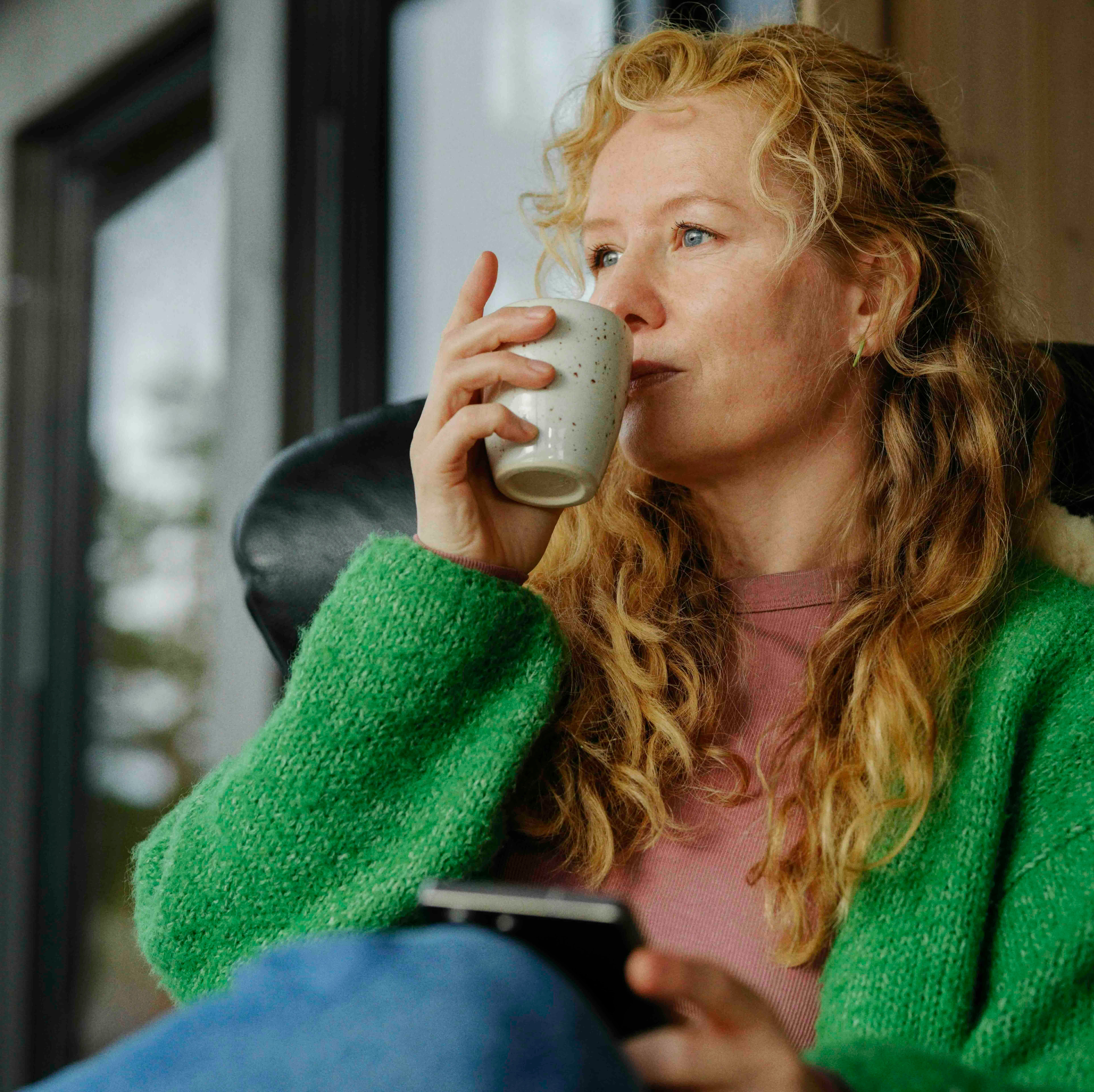 dame med kaffekopp og mobil med mitt telenor-appen