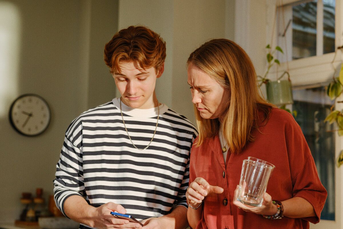 Ung gutt og dame som ser på en telefon