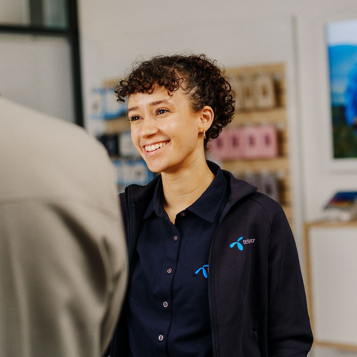 en medarbeider i telenorbutikken smiler til en kunde