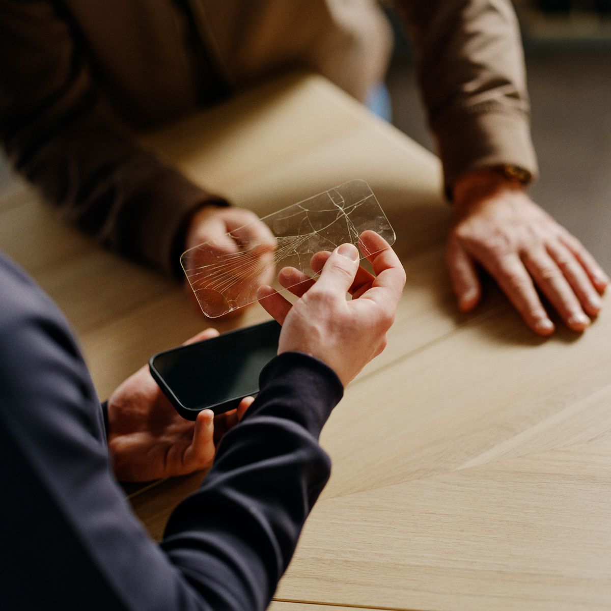 en medarbeider i telenorbutikken tar av en knust skjermbeskyttelse for en kunde