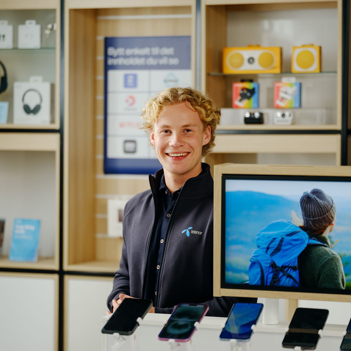 en mann som står klar i telenorbutikken for å hjelpe kundene