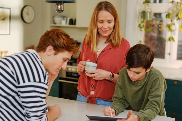 familie som står rundt et bord og ser på en iPad