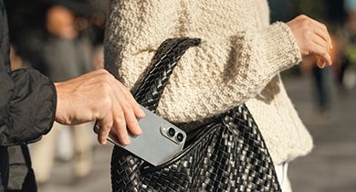 en hånd stjeler en samsungtelefon fra vesken til en dame