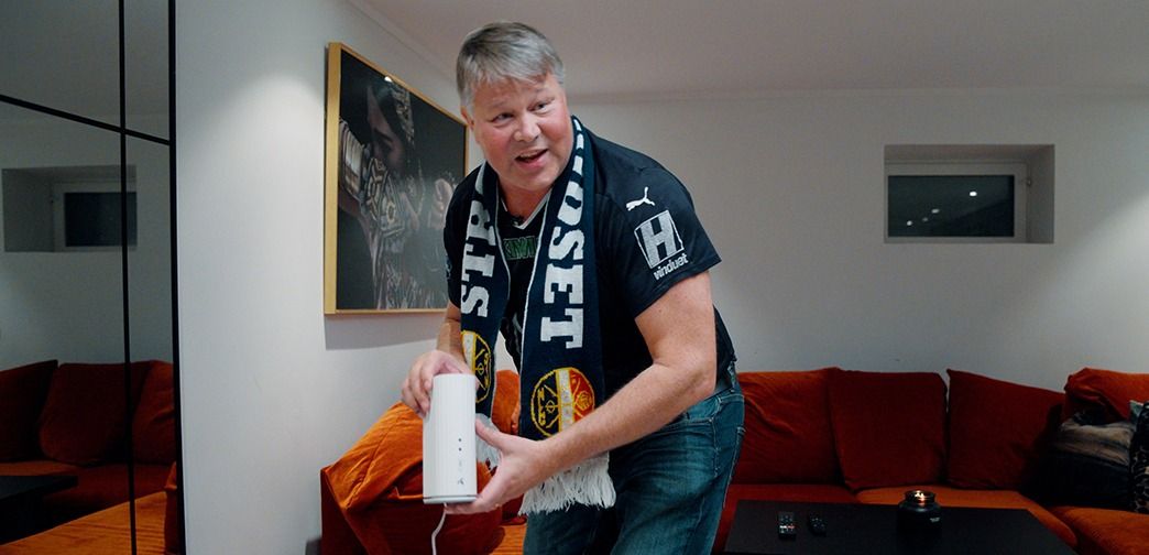 Person holder en wifi-forsterker fra Telenor i stue