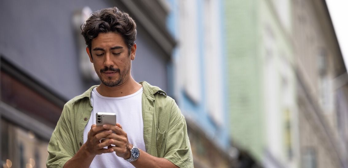 Mann med mobiltelefon reagerer på en falsk e-post fra egen mailadresse