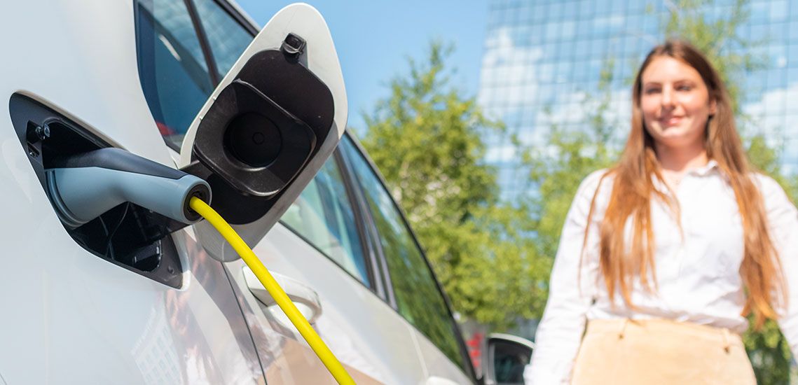 Elbil lades i urbant miljø med grønt og moderne bakteppe