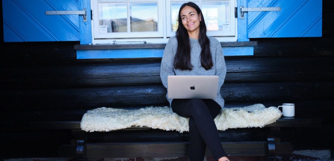 Kvinne sitter på benk og surfer via internett hytte