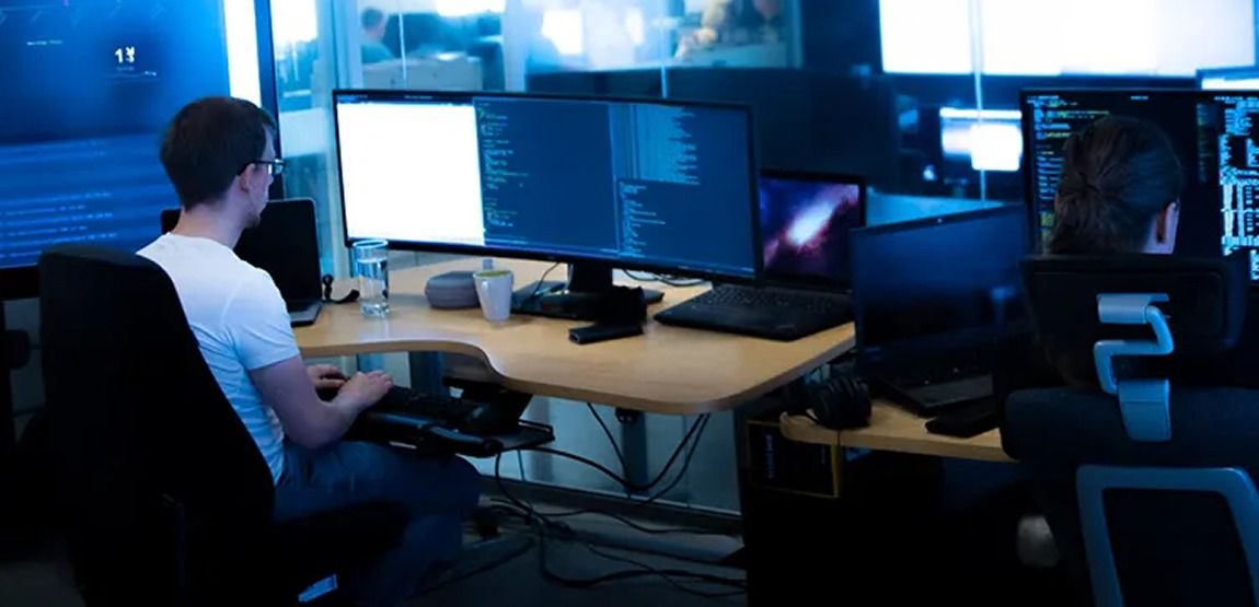 Programmeringsmiljø med to personer foran flere skjermer