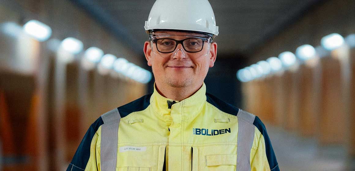 Person i gul arbeidsuniform og hjelm i industriell tunnel