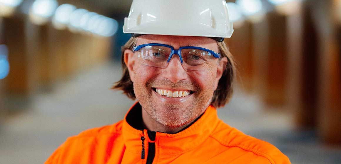 Henning Elvestad med hvit hjelm og oransje arbeidsklær i en industriell setting
