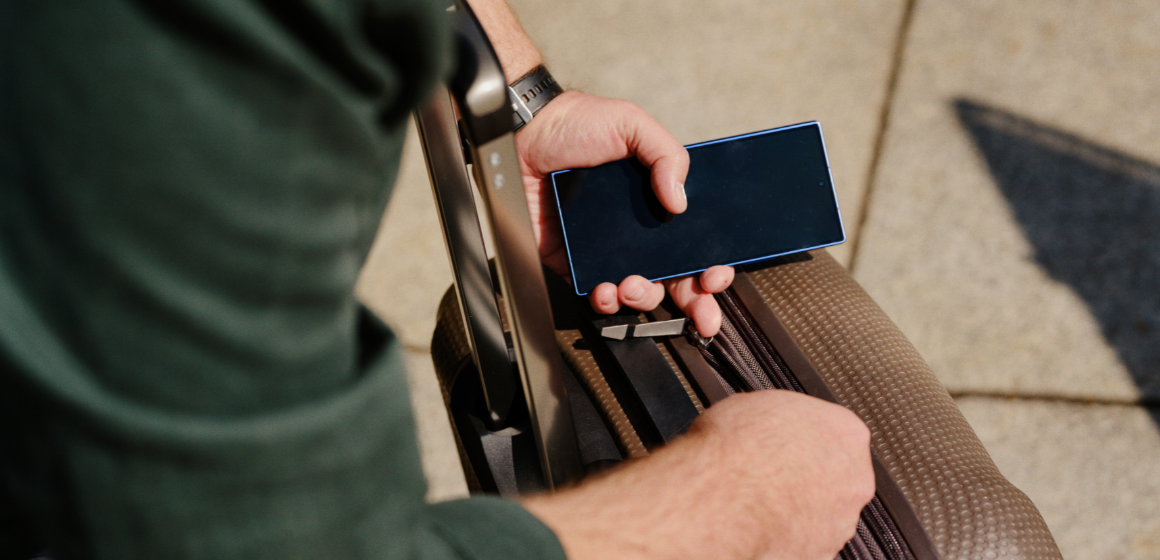 Mann er på reise med koffert og mobiltelefon