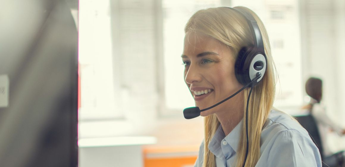 Dame med headset foran en PC