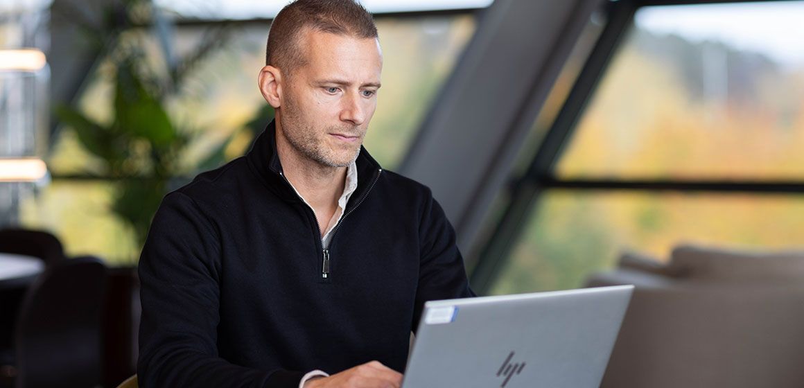 En person arbeider ved en bærbar PC i et moderne og lyst rom