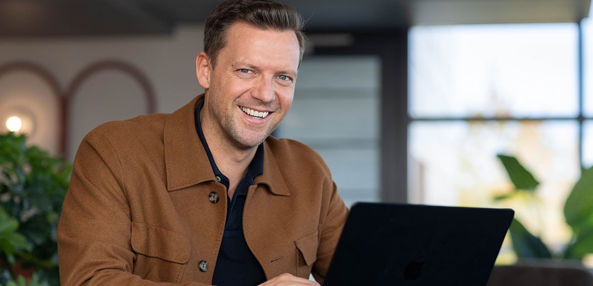 Person jobber foran en bærbar datamaskin i moderne omgivelser