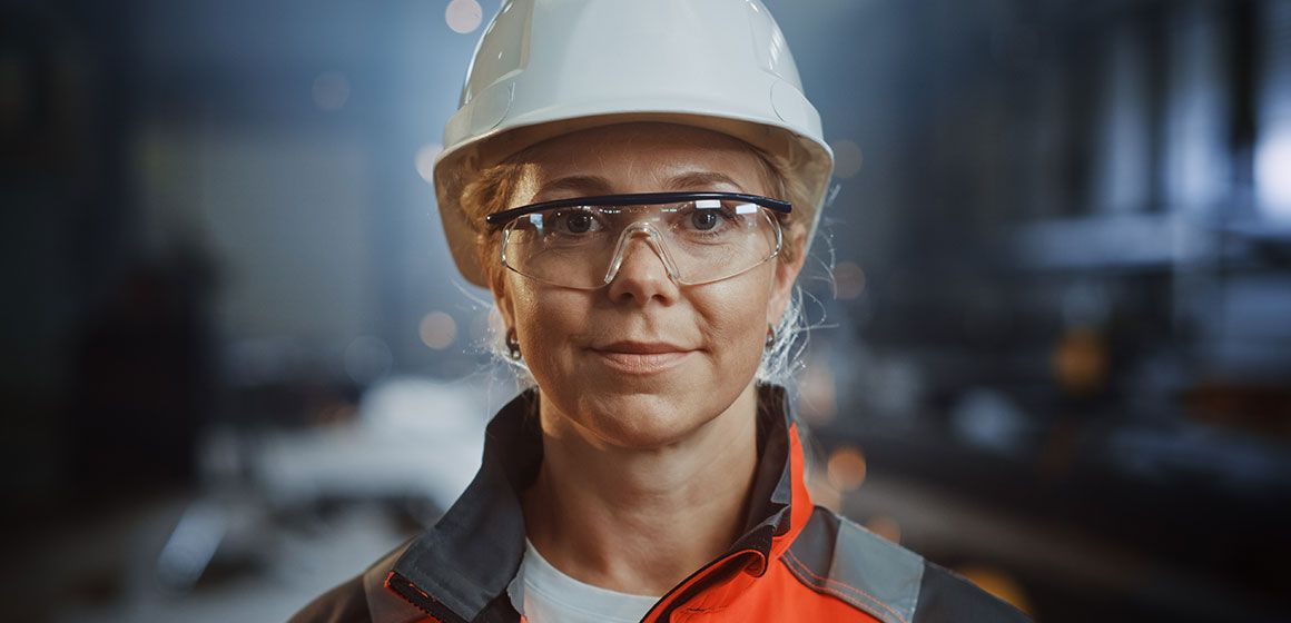 Person iført hjelm og refleksklær i industriell setting