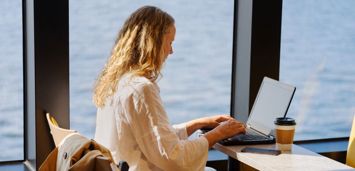 Mann sitter i baksete og jobber på pc vha avansert 5G og laptop connect