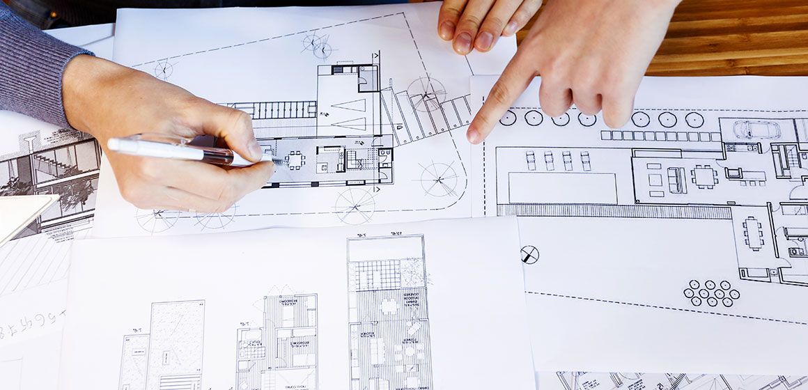 Personer diskuterer arkitekttegninger og plantegninger