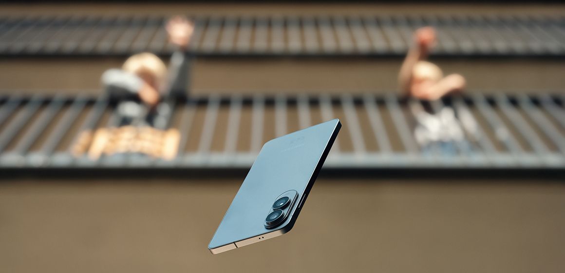 En svevende smarttelefon foran to uklare personer på en balkong