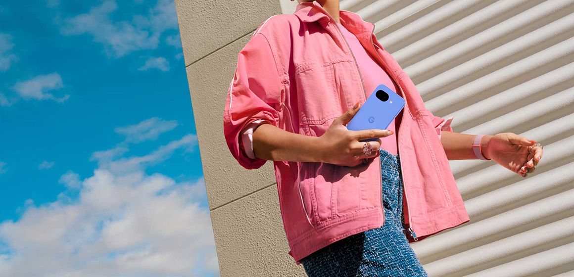 dame med en rosa jakke holder en google pixel 10a i hånden