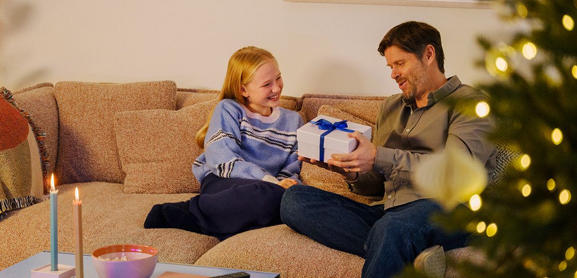 far og datter sitter i sofaen og utveksler årets beste julegaver