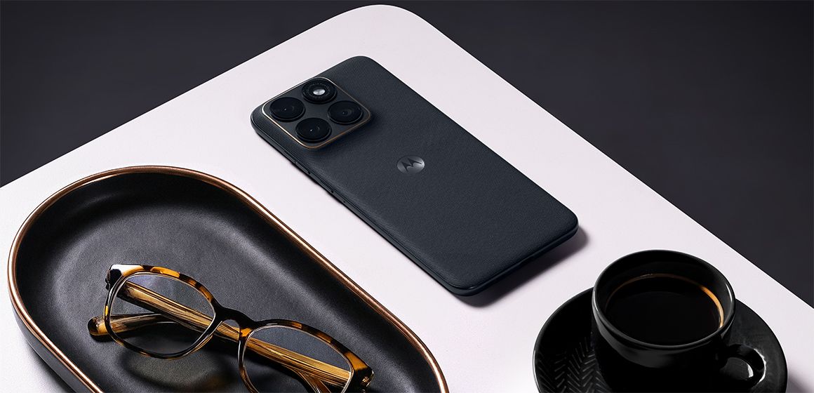 motorola edge 70 fusion i fargen silhouette ligger på et hvitt bord med briller og en kaffekopp