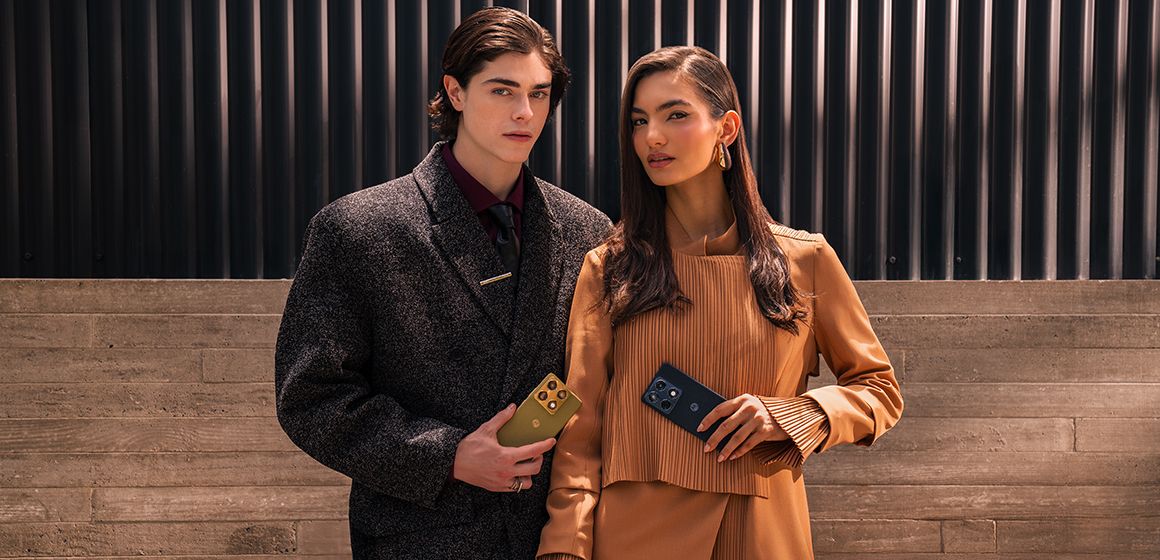 en mann og en dame i stilfult antrekk poserer med hver sin motorola signature i hånden