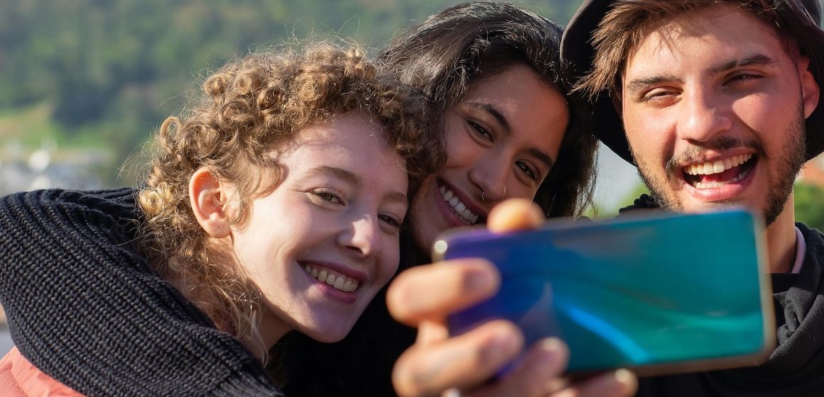 Tre personer tar en selfie med natur i bakgrunnen