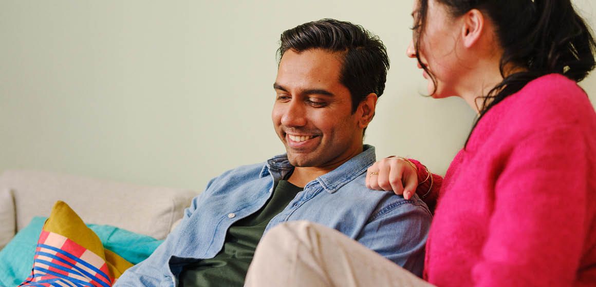 Et voksent par i sofa med nettbrett i hånda