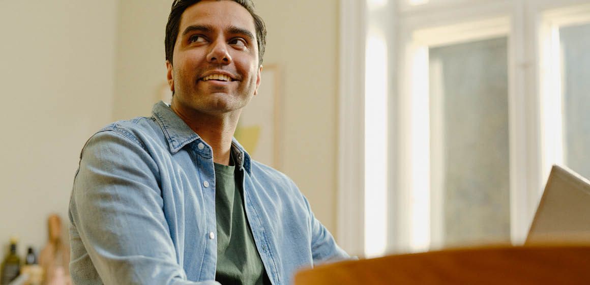 Person med dongeriskjorte og grønn t-skjorte foran et lyst vindu