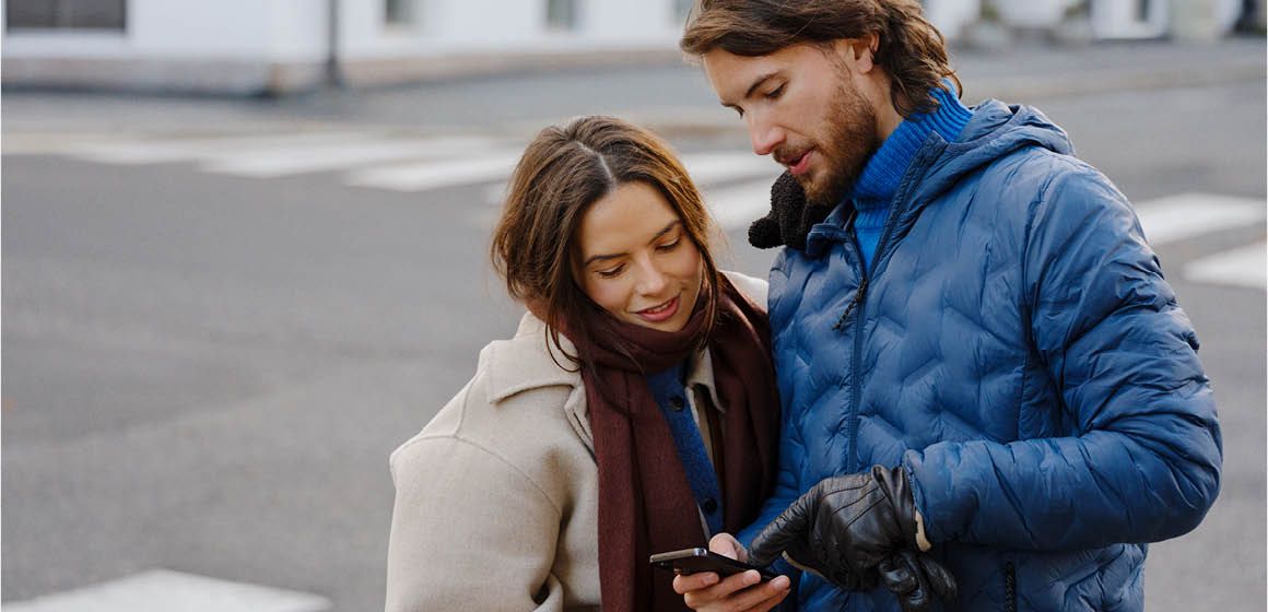 To personer kledd for kaldt vær sjekker en smarttelefon