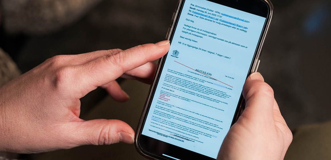 Hender holder en mobiltelefon med en e-post og dokument på skjermen