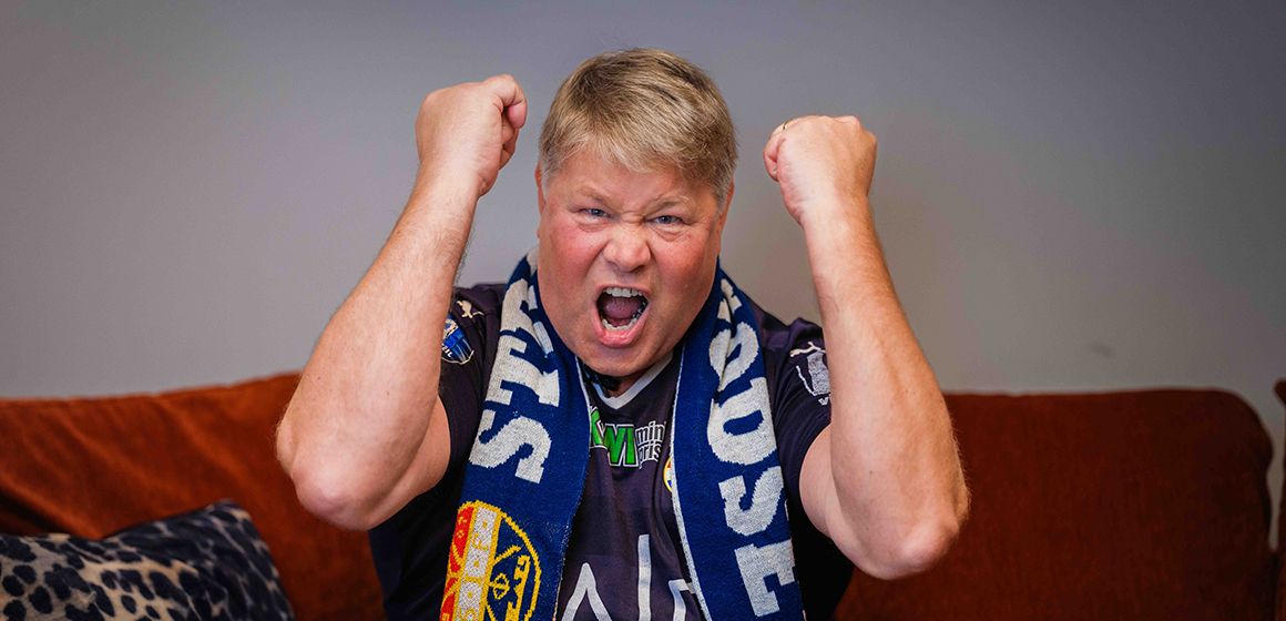 Person med fotballskjerf hever nevene