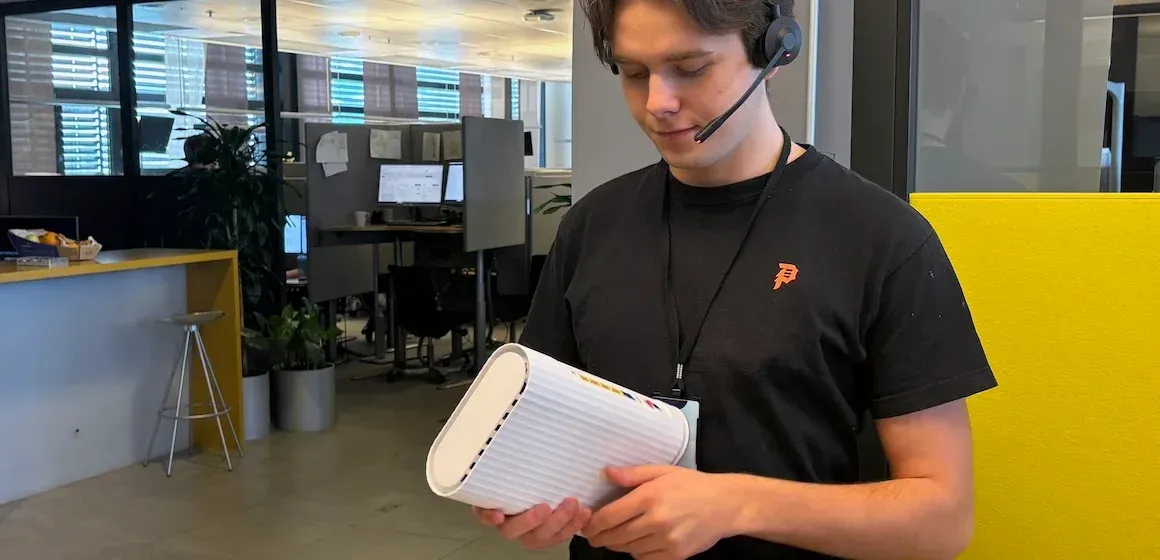 WiFI-ekspert i svart t-skjorte holder en hvit ruter i en kontorbygning