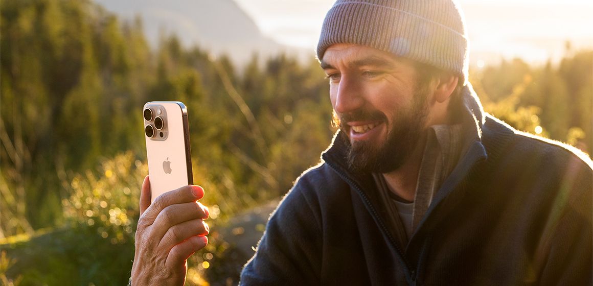 mann holder en iphone 16 pro i sandfarget titan
