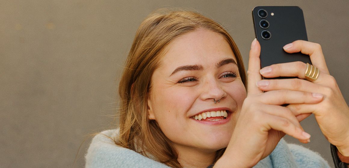 jente som smiler mens hun tar bilde av noe med galaxy s25