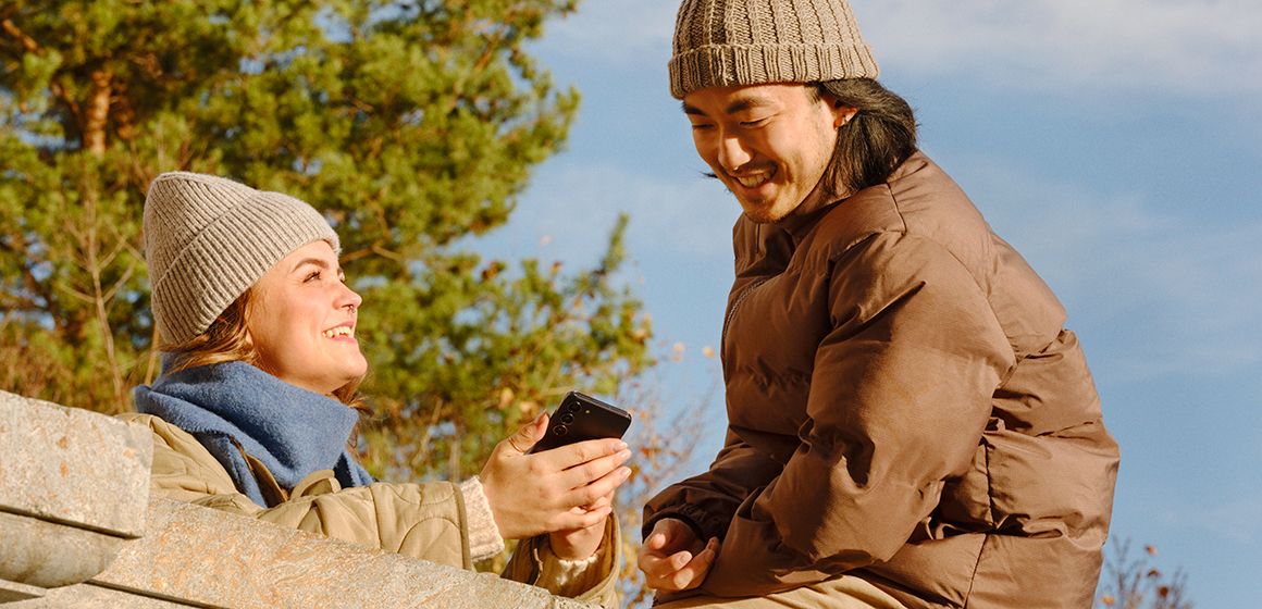 Jente som viser noe morsomt på mobilen til en gutt