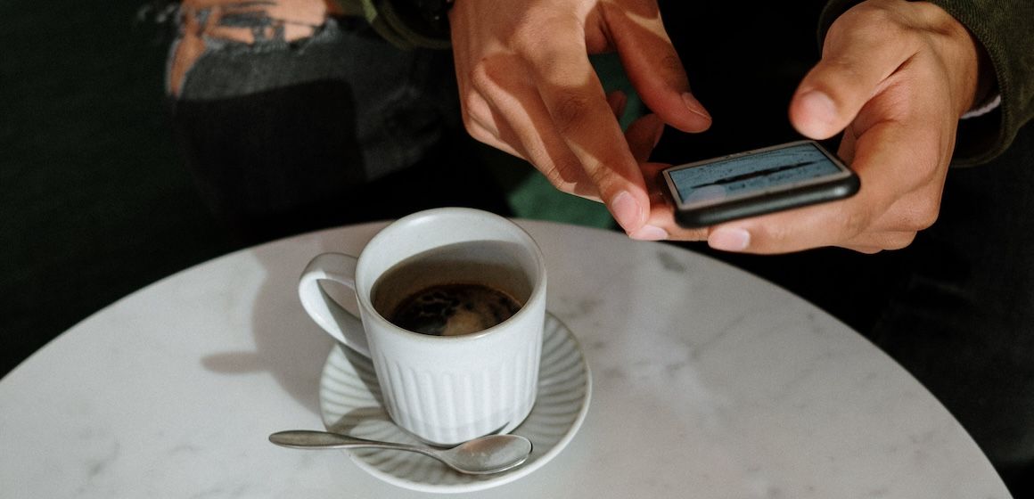 På kafé med kaffekopp og mobil