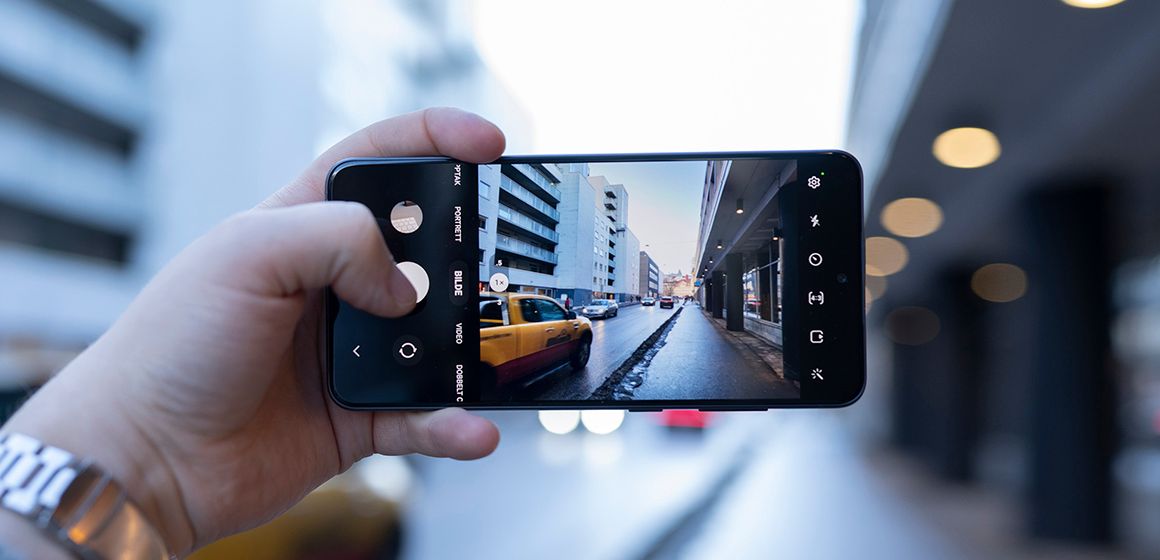 en mann viser frem kameraet på galaxy s21 fe