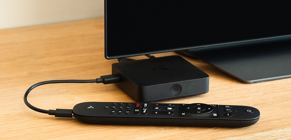 T-we-fjernkontroll og TV-boks på bordet.