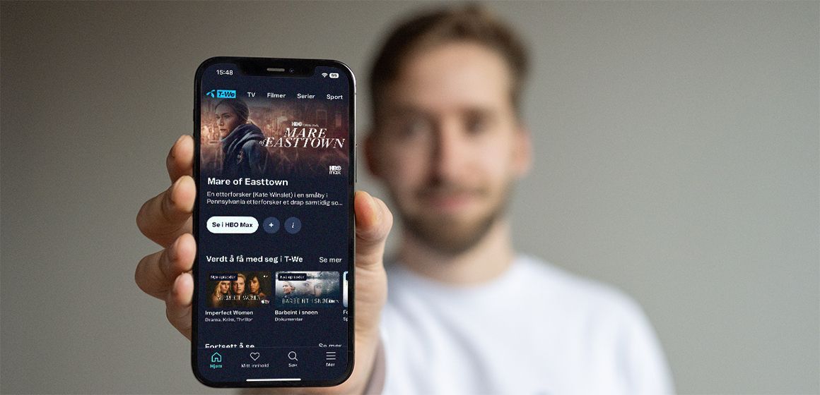 Hånd holder mobil med t-we appen.