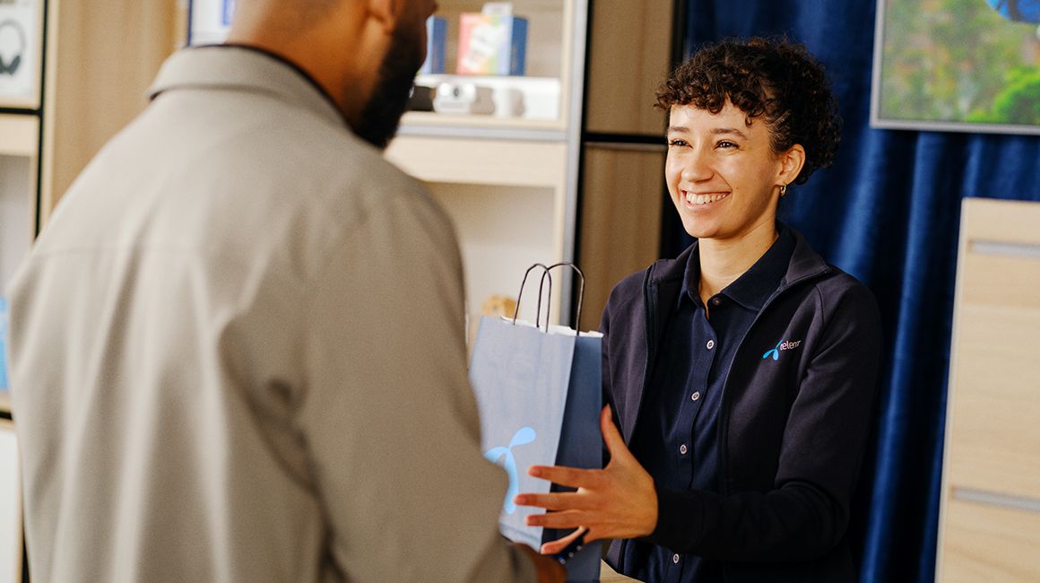 Mor og datter sitter ved frokostbordet og ser på noe morsomt på mobilen