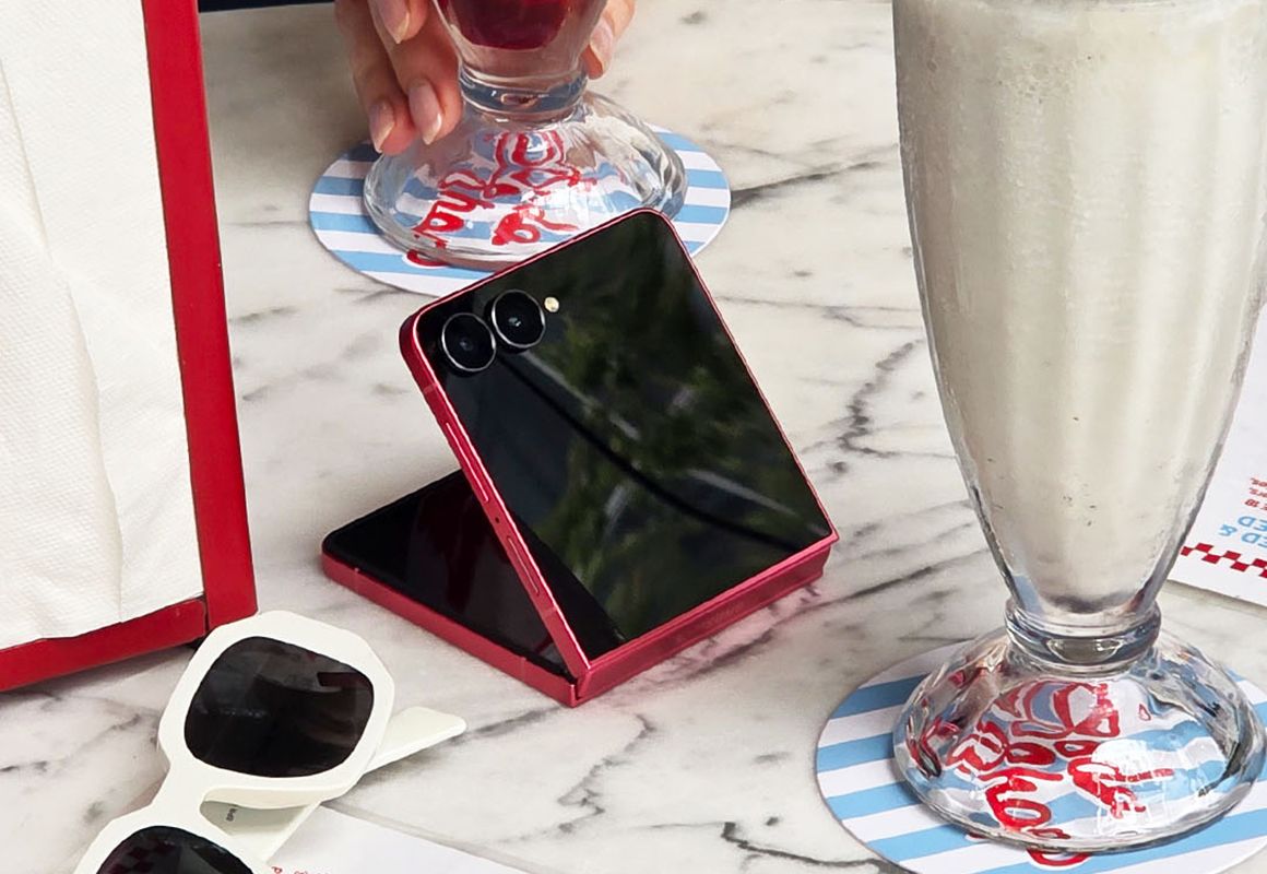 Galaxy Z Flip7 i coral red på et marmorbord med milkshake ved siden av