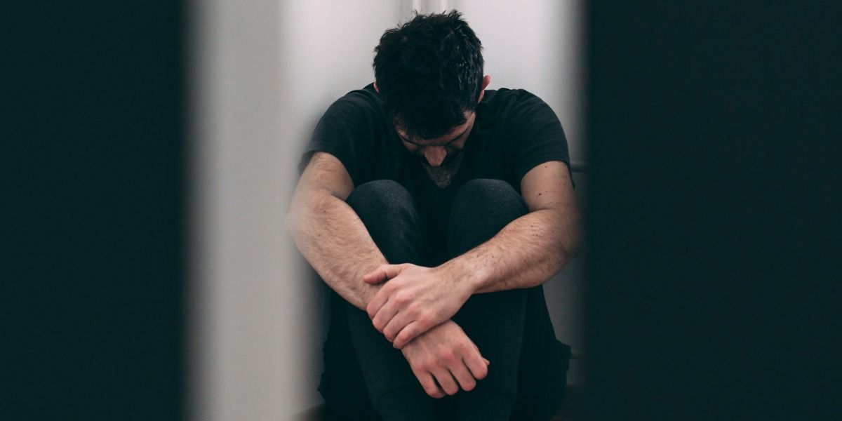 Bilde som viser en mann sitte i fosterstilling på gulvet, og som har opplevd pornosvindel.
