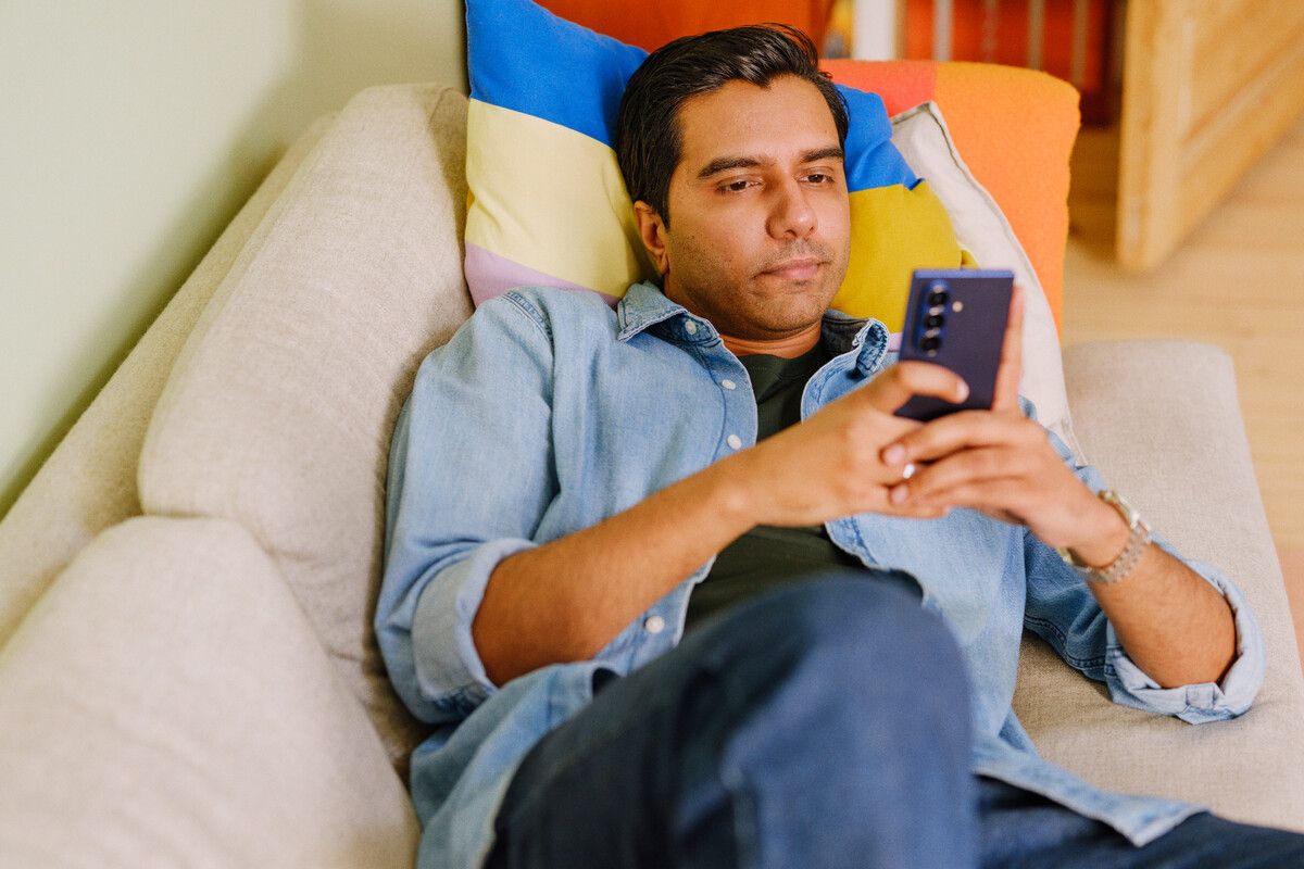 Mann med telefon i sofa