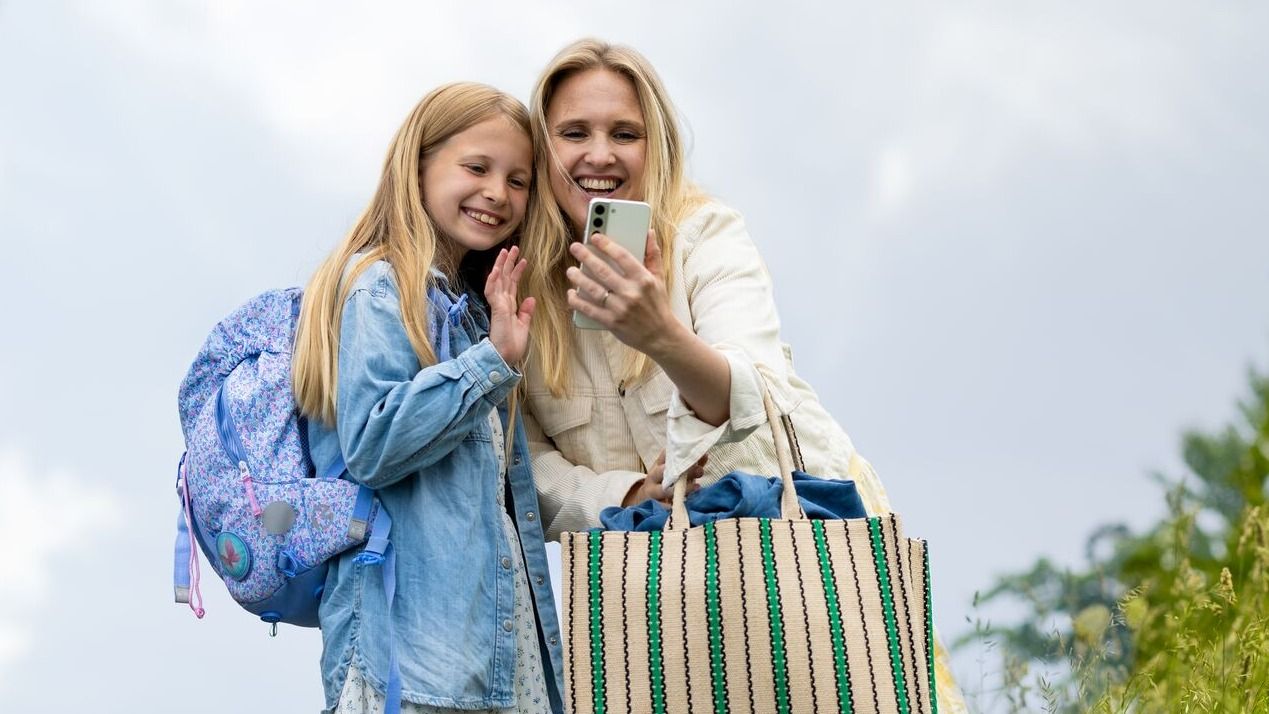 Mor og datter ser på mobilen sammen. Datter har abonnementet Liten 5 GB data fra Telenor