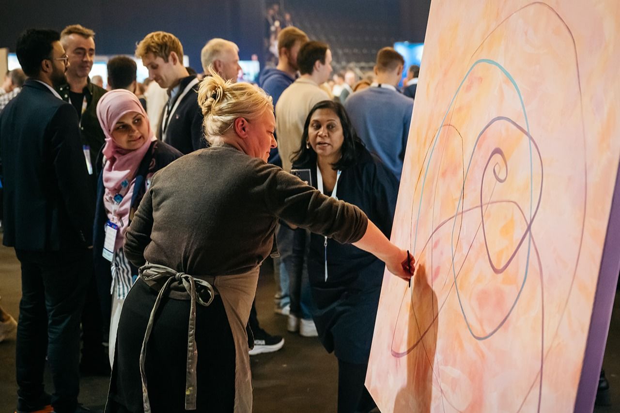 Kunstner maler abstrakt verk, omgitt av nysgjerrige tilskuere.